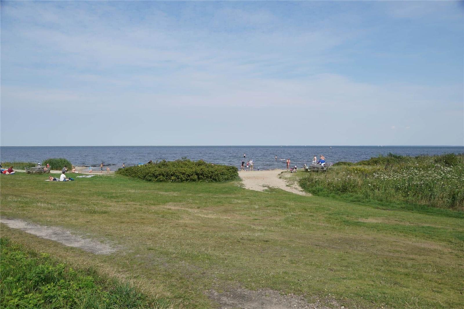 Grasfläche mit Sandplatz und Blick auf das Wasser
