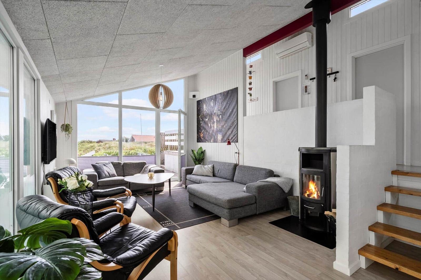 Wohnzimmer mit grauem Sofa, TV und großem Fenster zur Aussicht.