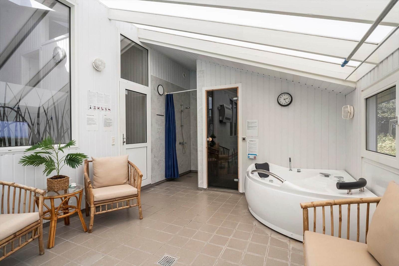 Wohnzimmer mit Kamin, Sofa, Sessel und großem Fenster. Treppenhaus rechts.