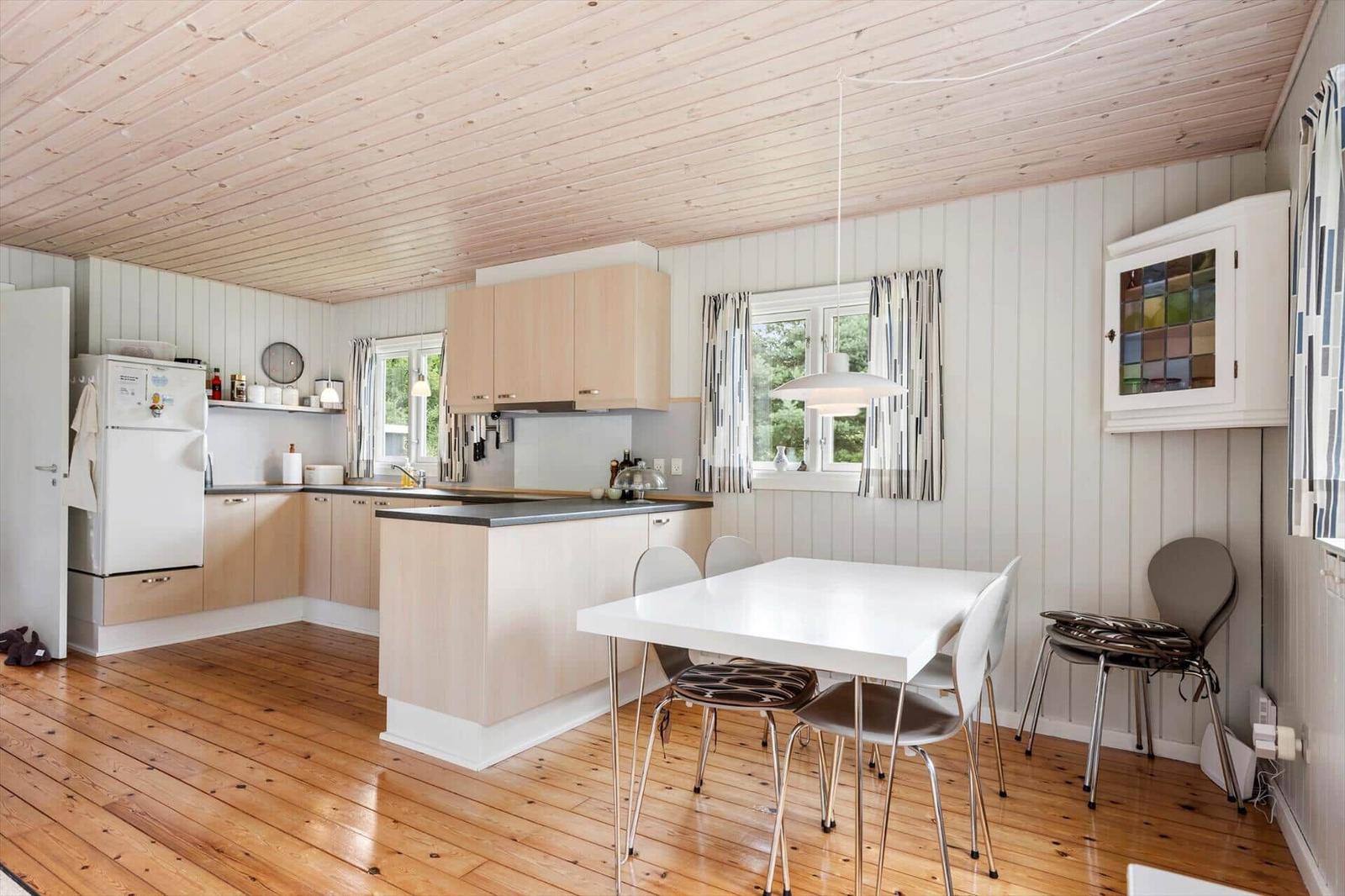 Two wicker chairs and a fur ottoman are in a room with wood paneling and a window.