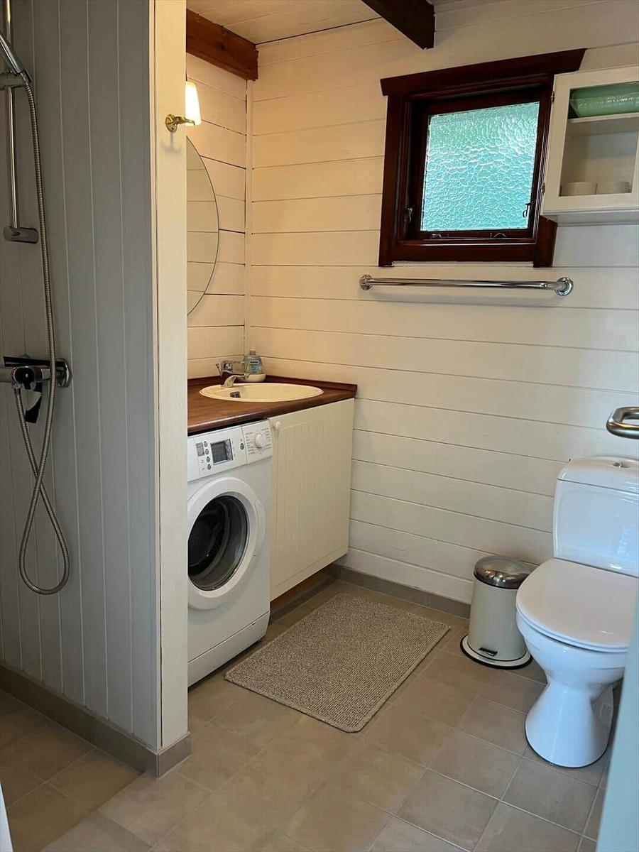 Bootshäuser am Wasser mit Holzstegen und grüner Uferlandschaft.