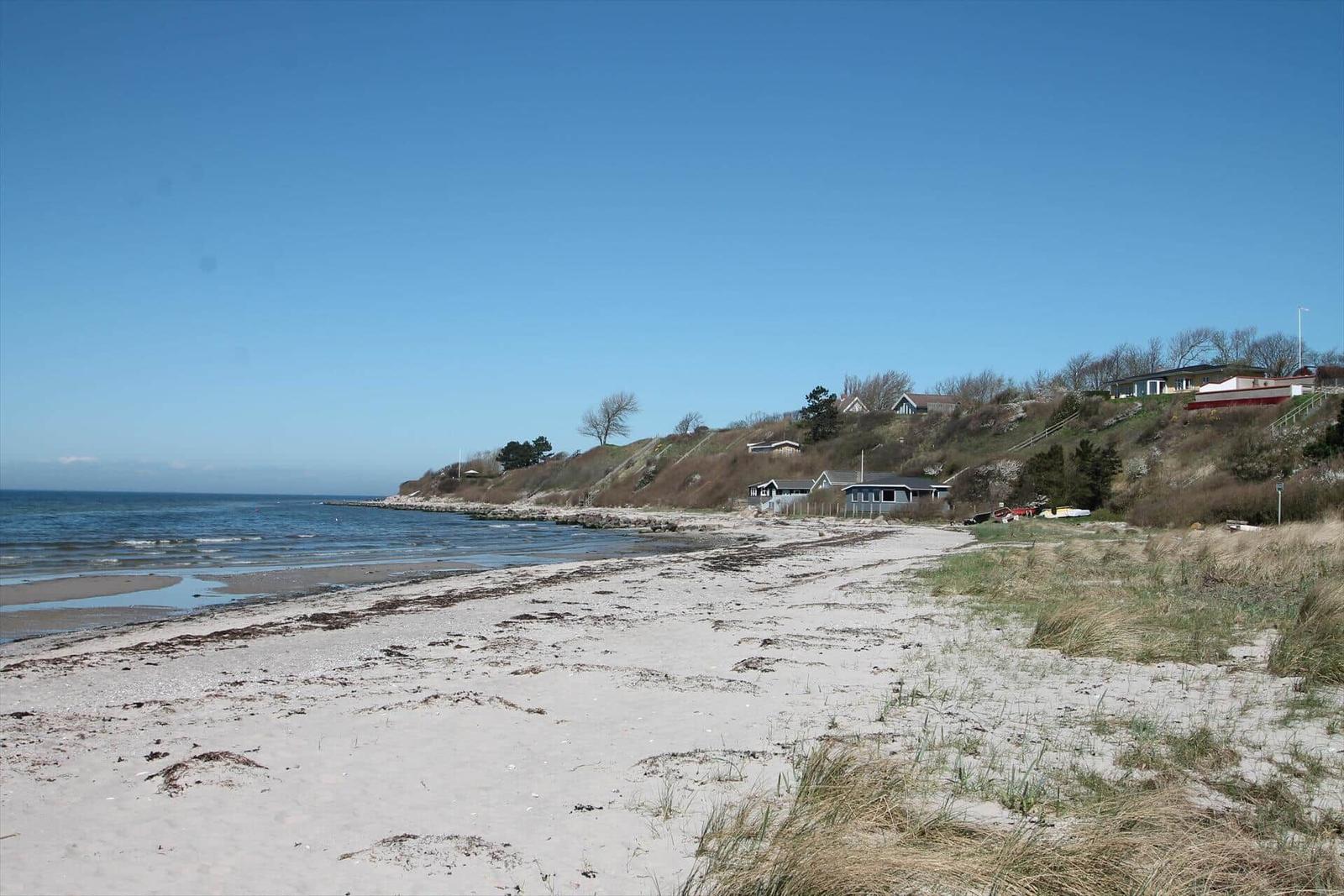 Küstenhaus mit Boot am Strand, Blick auf ruhiges Meer und felsiges Ufer.