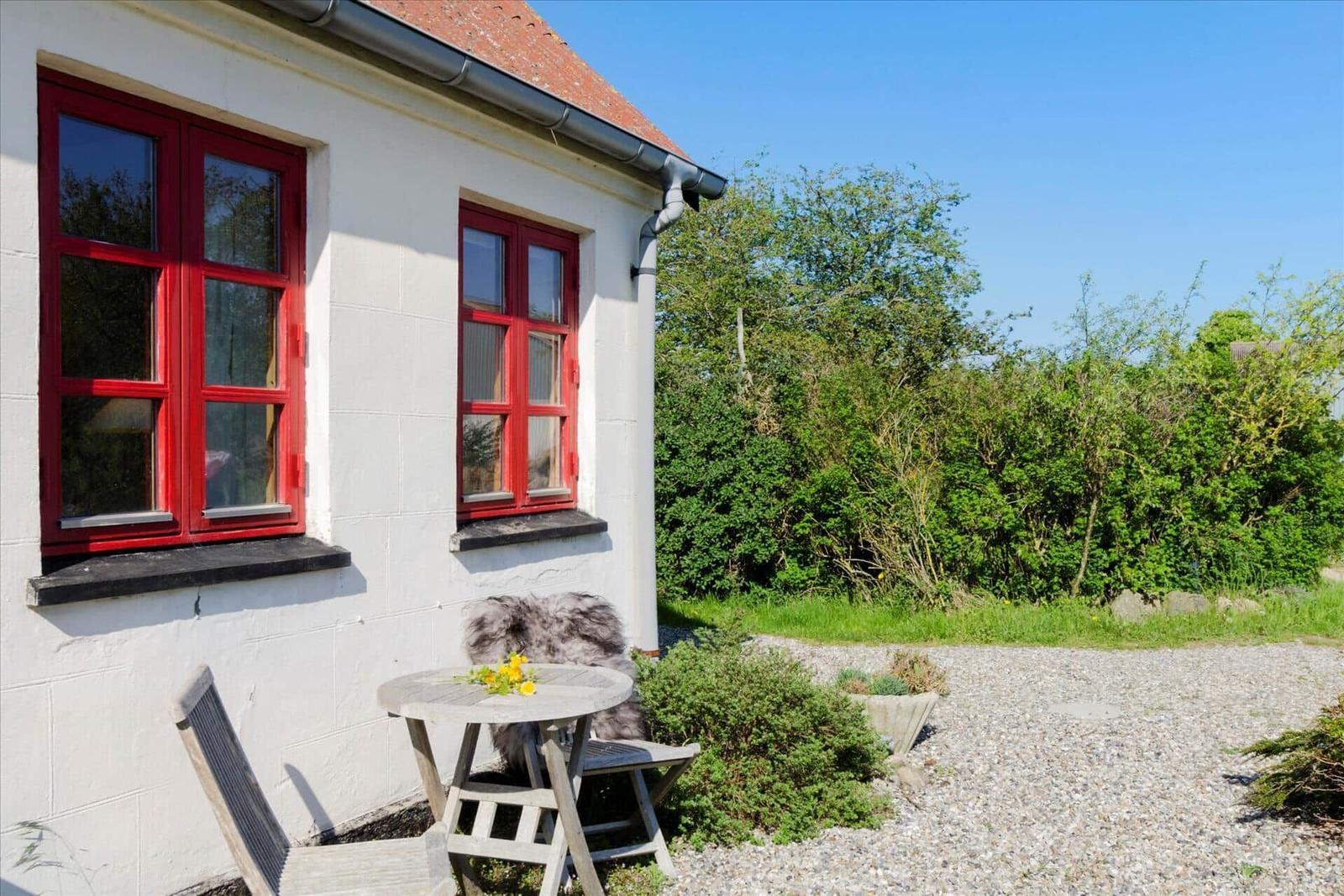 Grüner Garten mit Tisch und Stühlen. Im Hintergrund Hügel und Felder.