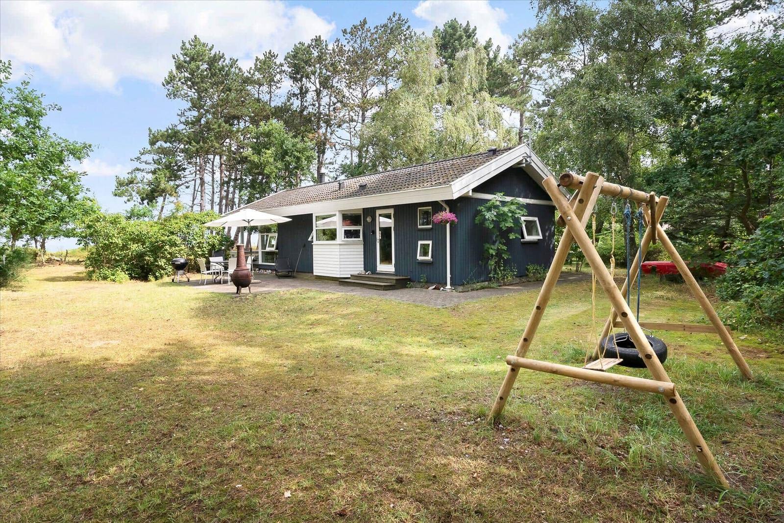 Roter Holzsaal mit Terrasse, Bootssteg und drei Motorbooten im Wasser.