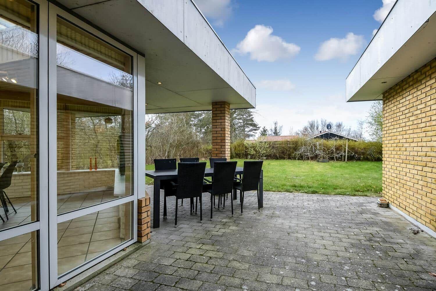 Modern villa with terrace and garden. Glass facade and wooden doors visible.