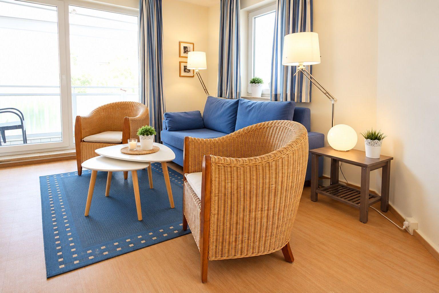 Living room with sofa, two chairs, table, and rug. Windows with curtains and lamps.