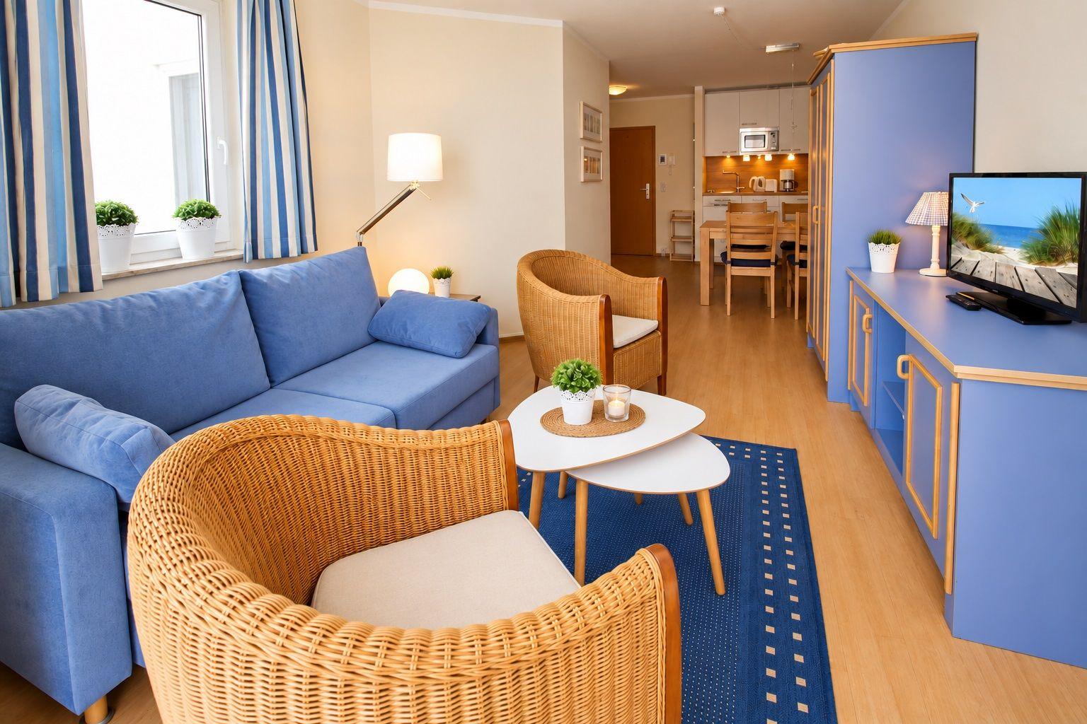 Living area with sofa, chairs, and kitchen area in the background.