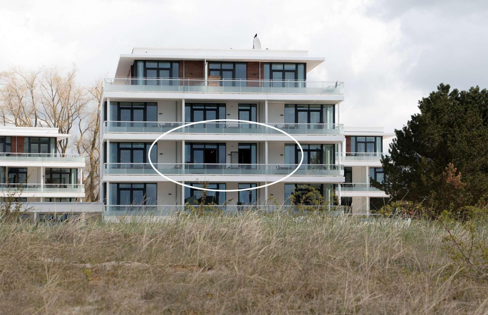 Moderne Wohnung mit Balkon, umgeben von Bäumen und einem gepflasterten Weg.