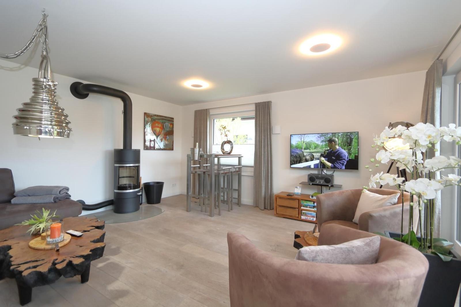 Ein Wohnzimmer mit braunem Sofa, orangefarbenen Kissen und einem rustikalen Holztisch.