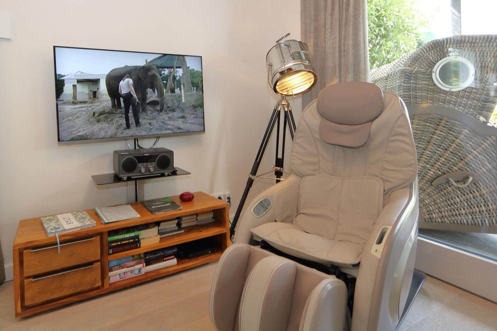 Wohnzimmer mit Sofa, Sessel und Holztisch. An der Wand hängt ein Bild mit Regenschirmen.