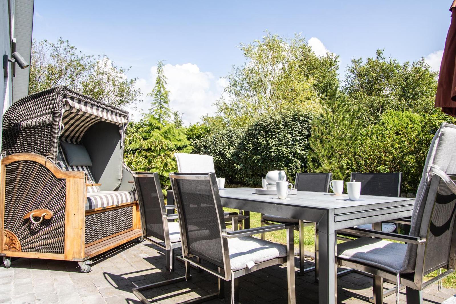 Hinterhof mit Garten, Sitzgelegenheit und Sonnenschutz. Grünflächen und Pflanzen umgeben den Außenbereich.