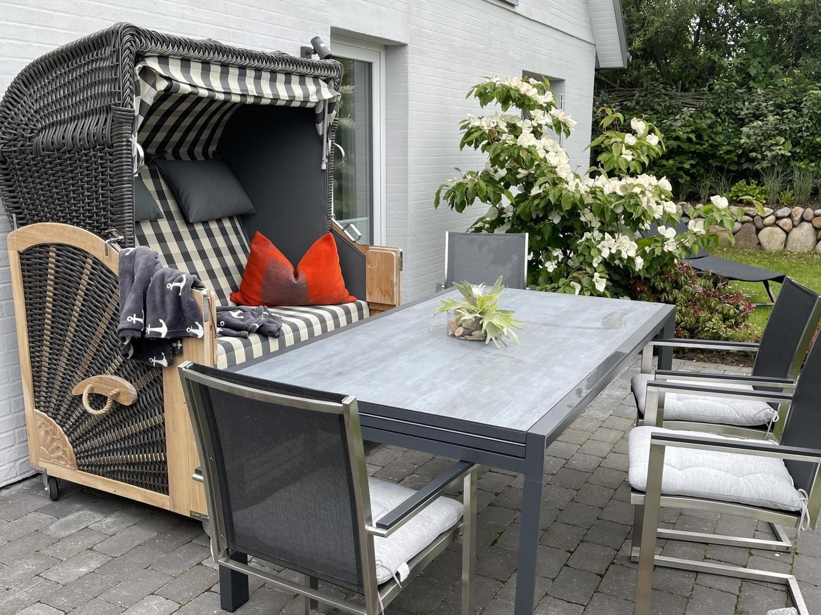 Garten mit Liegestuhl, Blumen und Steinmauer