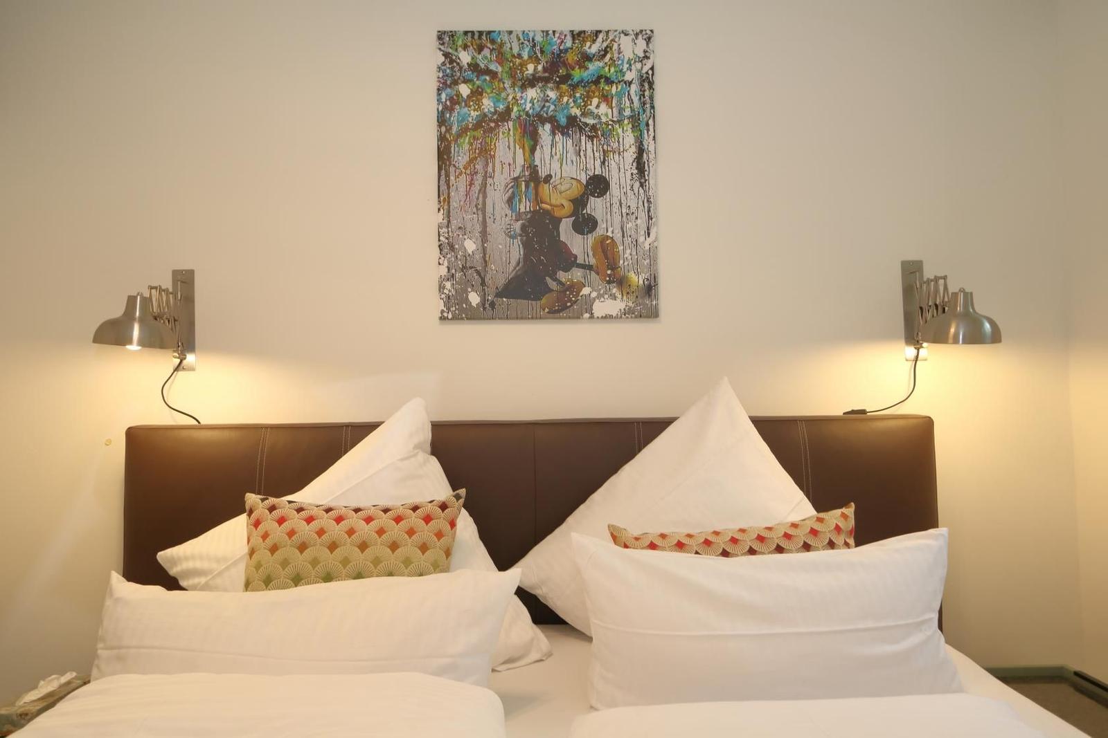 Schlafzimmer mit Bett, Kleiderschrank und Wandbild.
