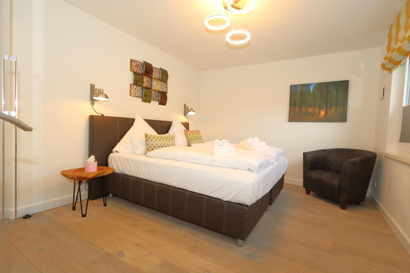 Schlafzimmer mit Doppelbett, Spiegelschrank und Wandkunst.