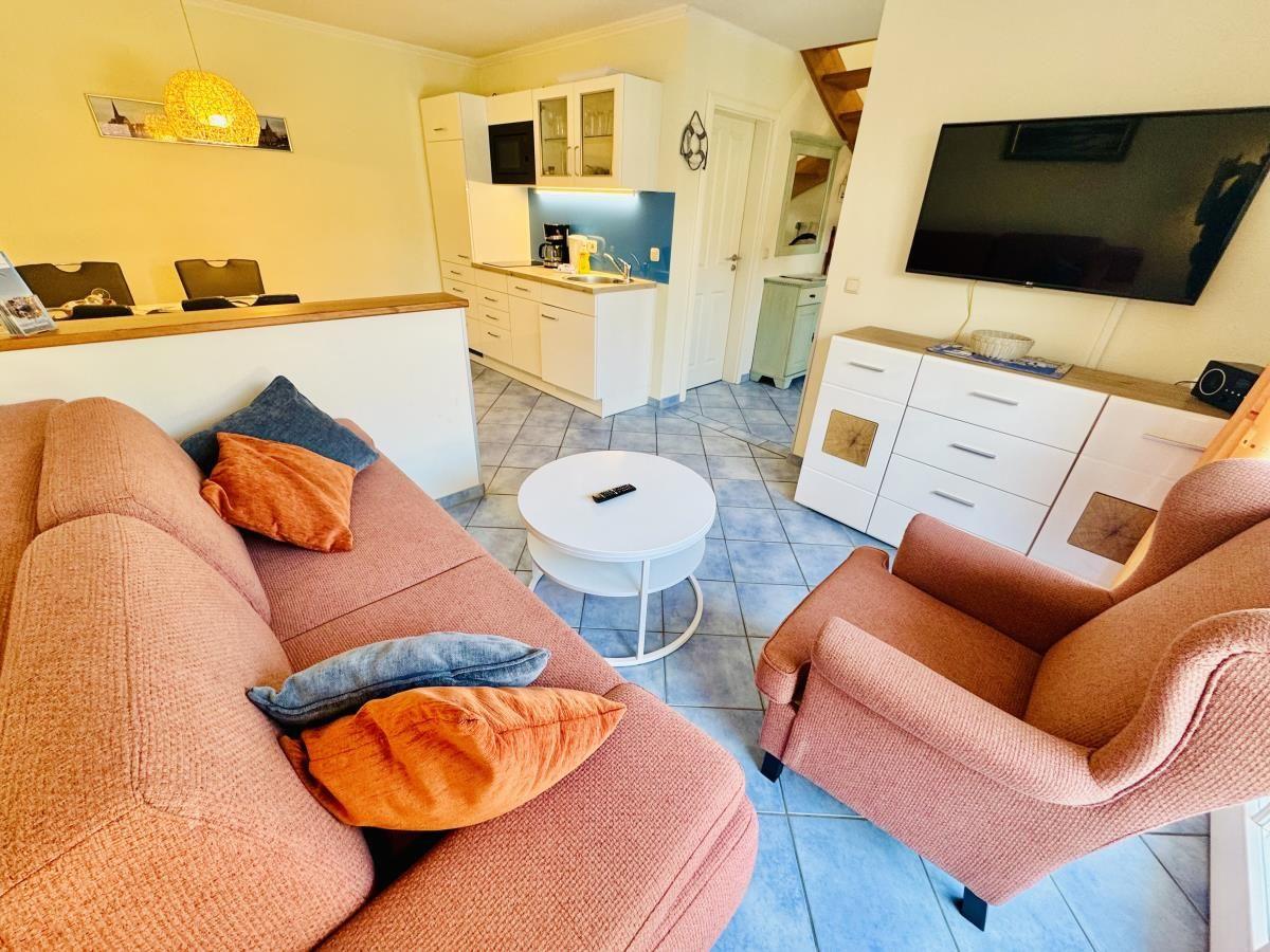 Essbereich mit Tisch und Stühlen, Wohnbereich mit Sessel und Terrassentür.