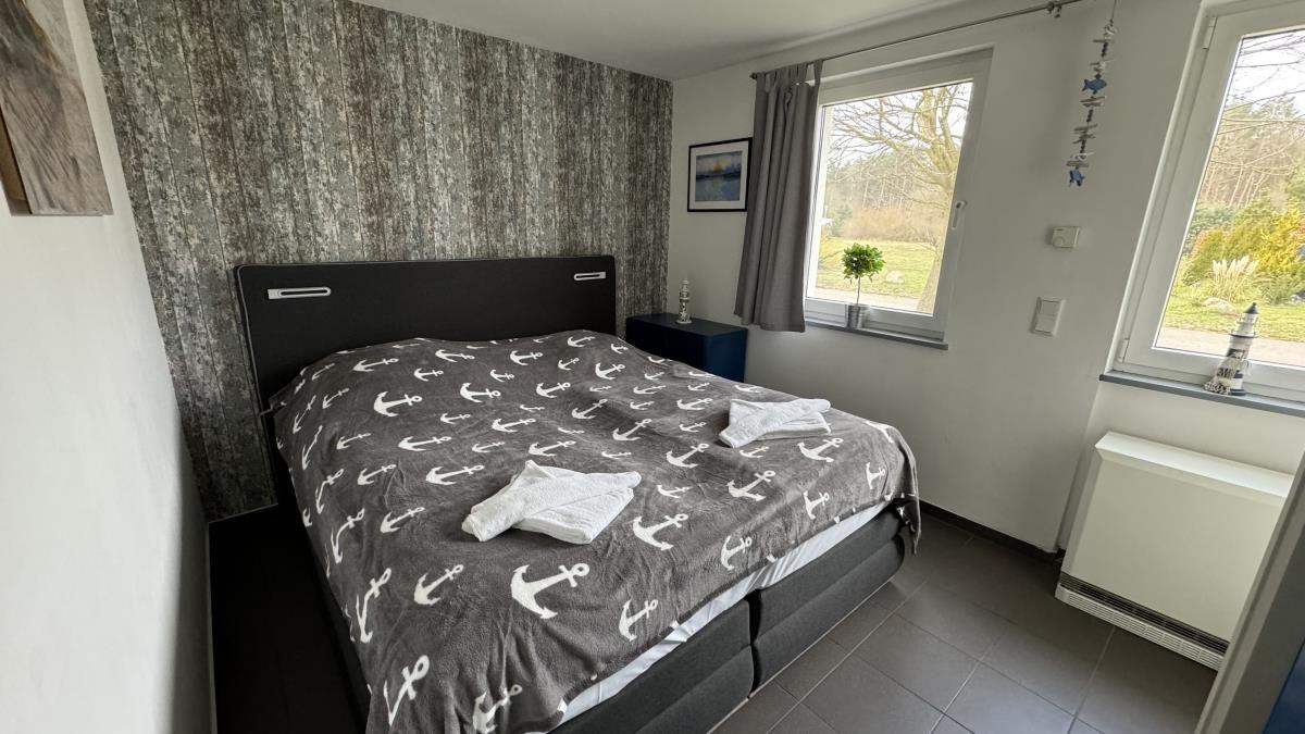 Schlafzimmer mit Doppelbett, Holzmöbel und Blick auf Garten.