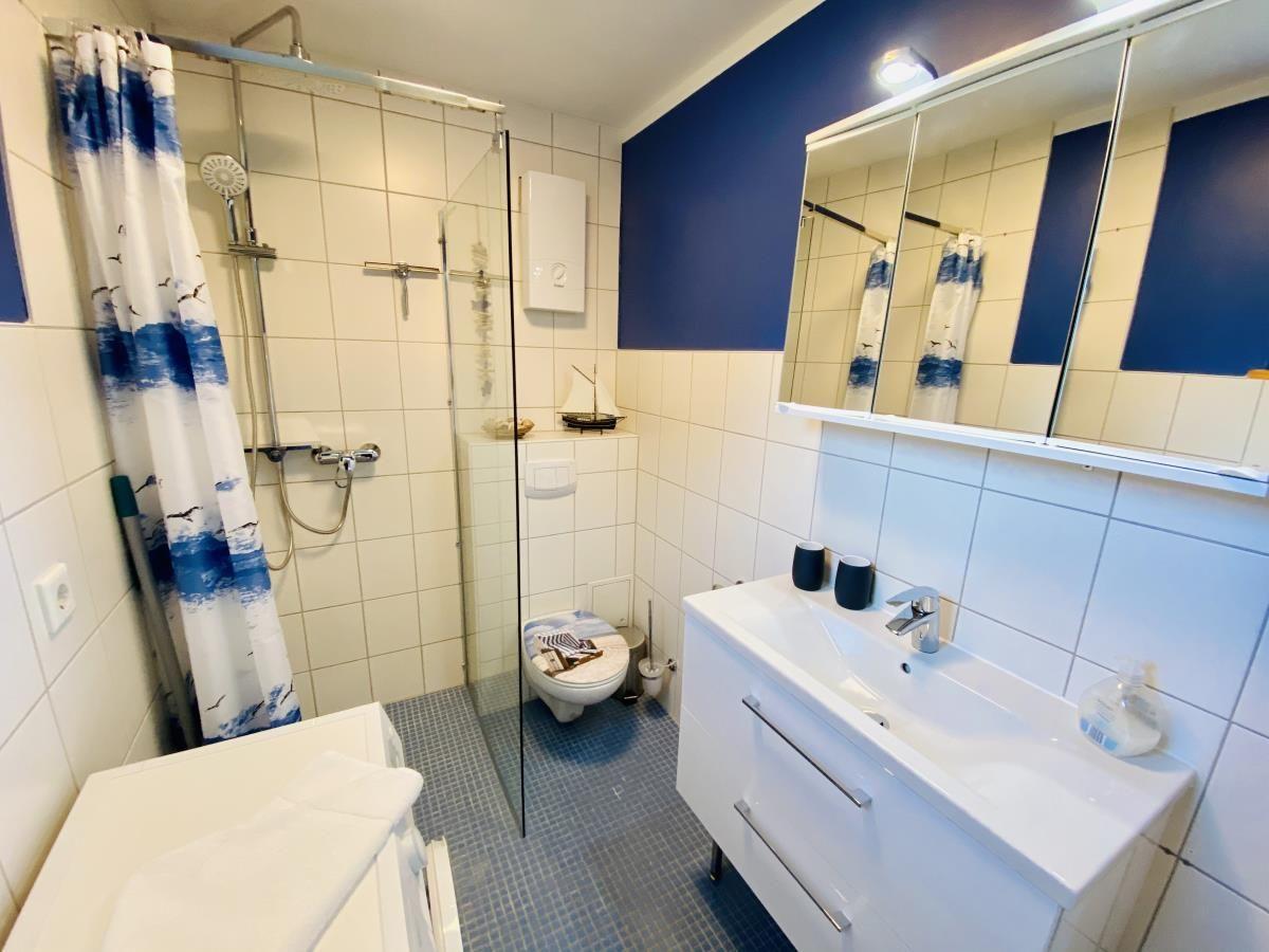 Badezimmer mit Dusche, Toilette und Waschbecken mit Spiegelschrank.