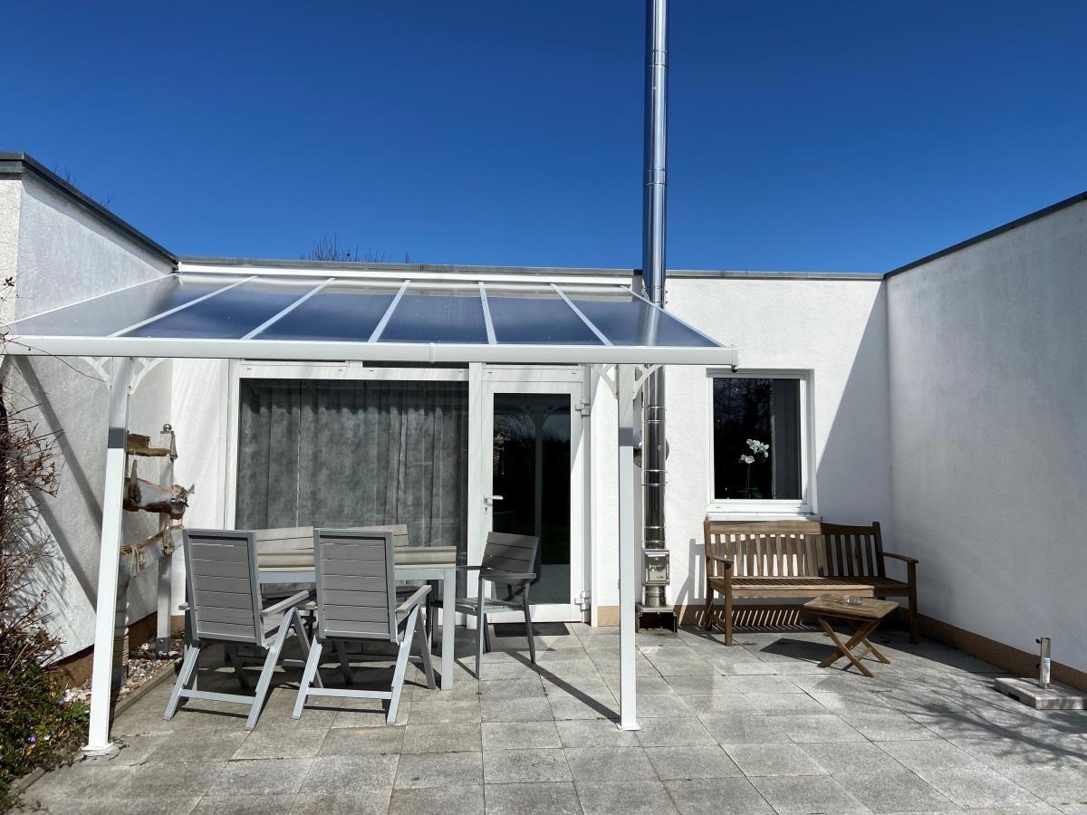 Moderne weiße Villa mit Garten und Eingangstür. Himmel mit Wolken.