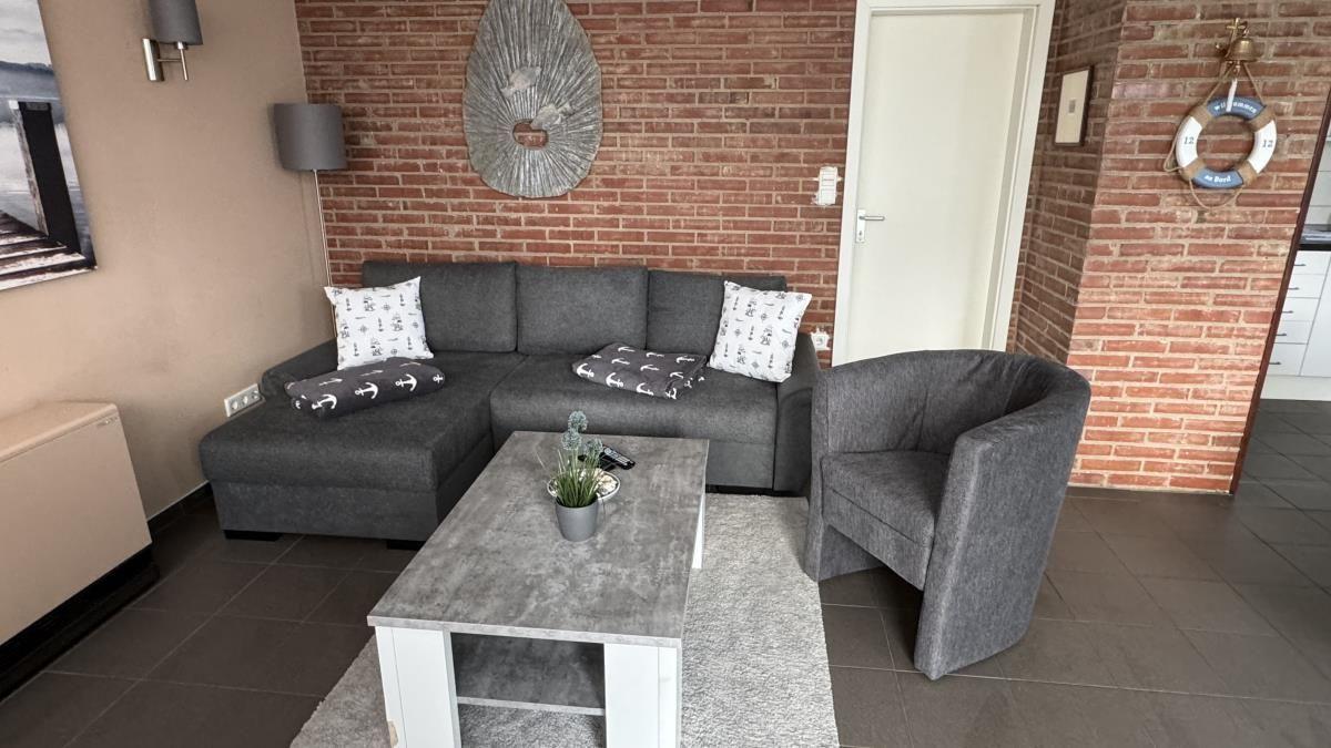 Esszimmer mit Tisch, Stühlen und Holzofen. Durchgang zur Terrasse mit Garten.