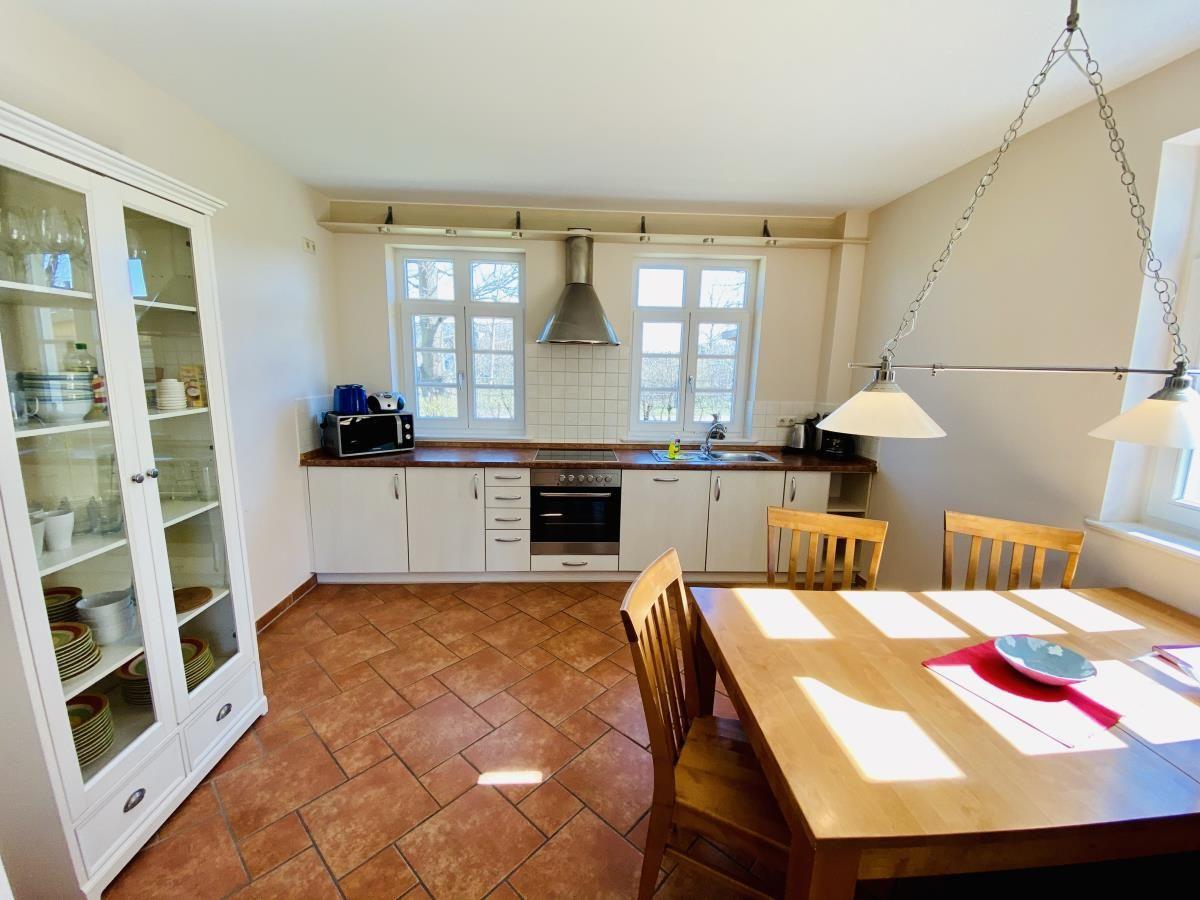 Schlafzimmer mit Holzbett, Nachttisch und Fenster mit Vorhängen.