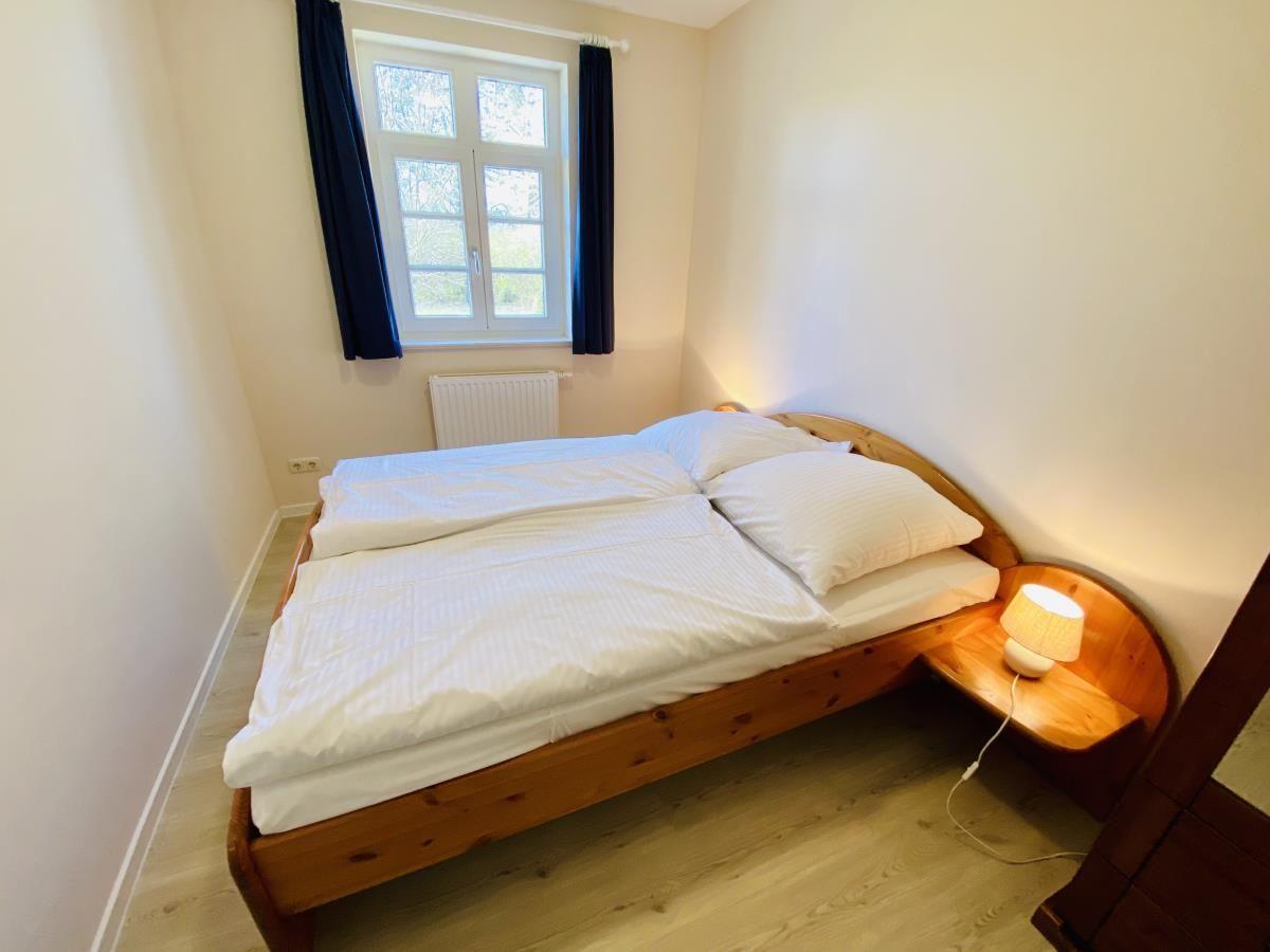 Badezimmer mit Badewanne, Toilette und Waschbecken. Fenster, Heizung und Fliesen sichtbar.