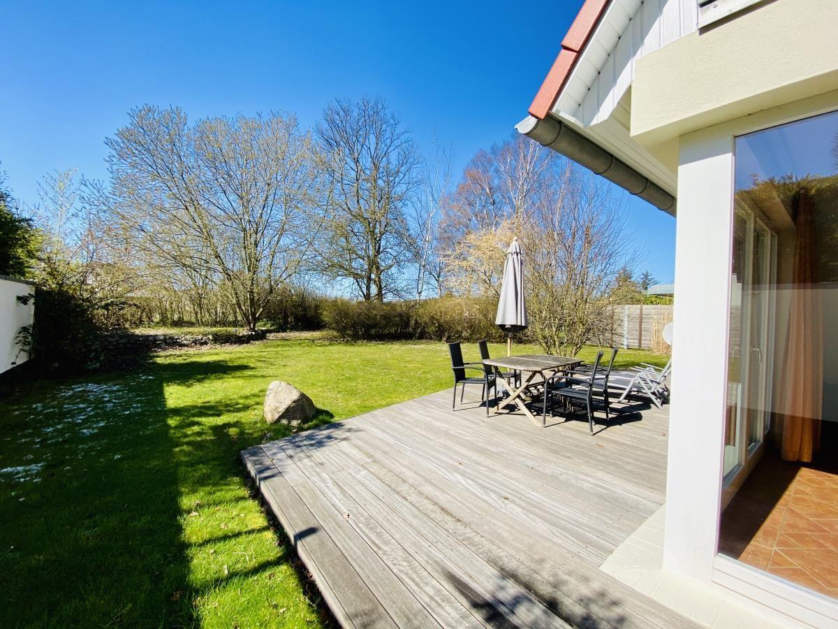 Wohnzimmer mit Sofa, Couchtisch und TV. Terrasse mit Gartenblick.