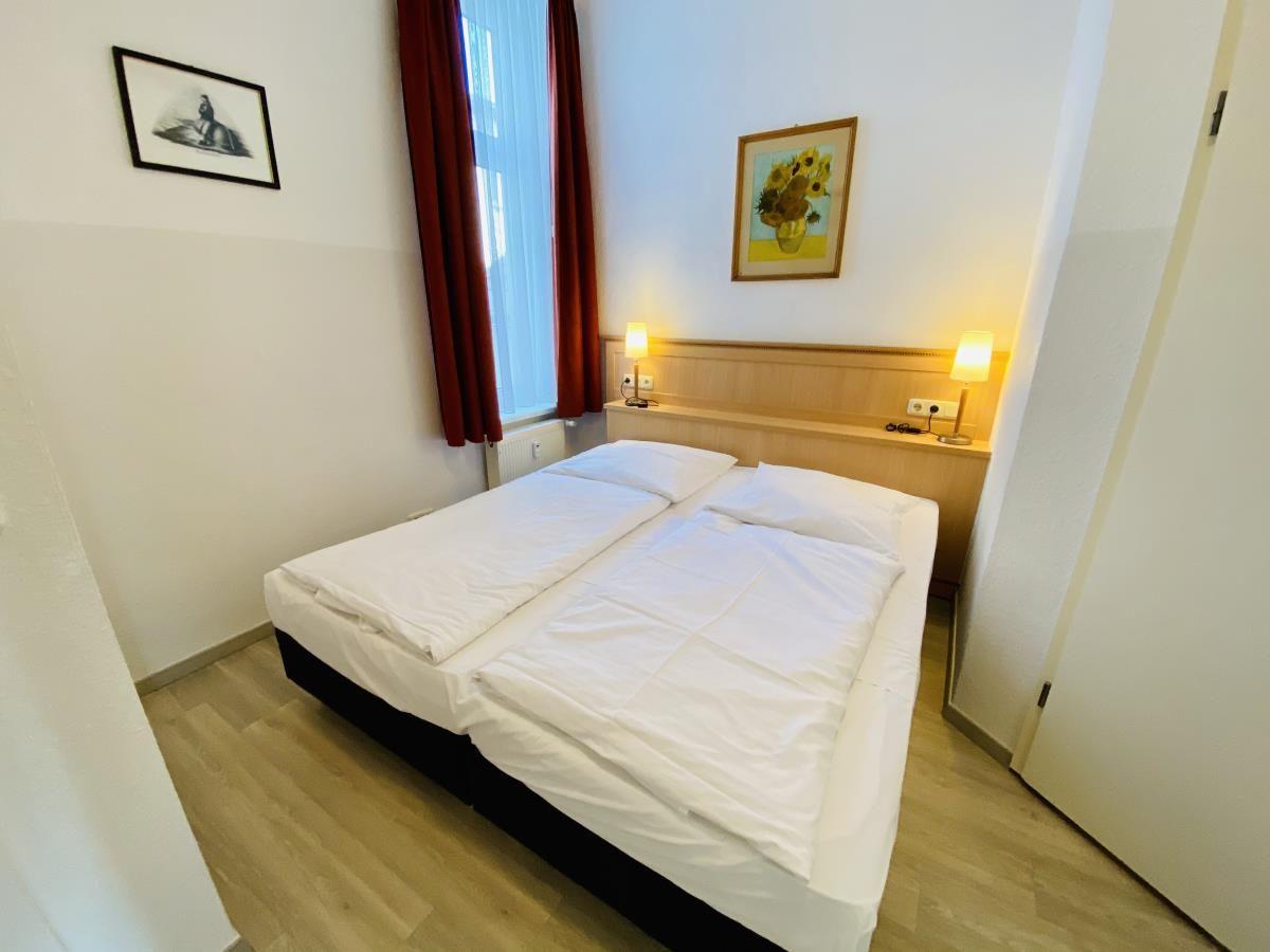 Holztreppe mit Teppichstufen und goldener Geländerleiste führt in einen Flur mit Kronleuchter.