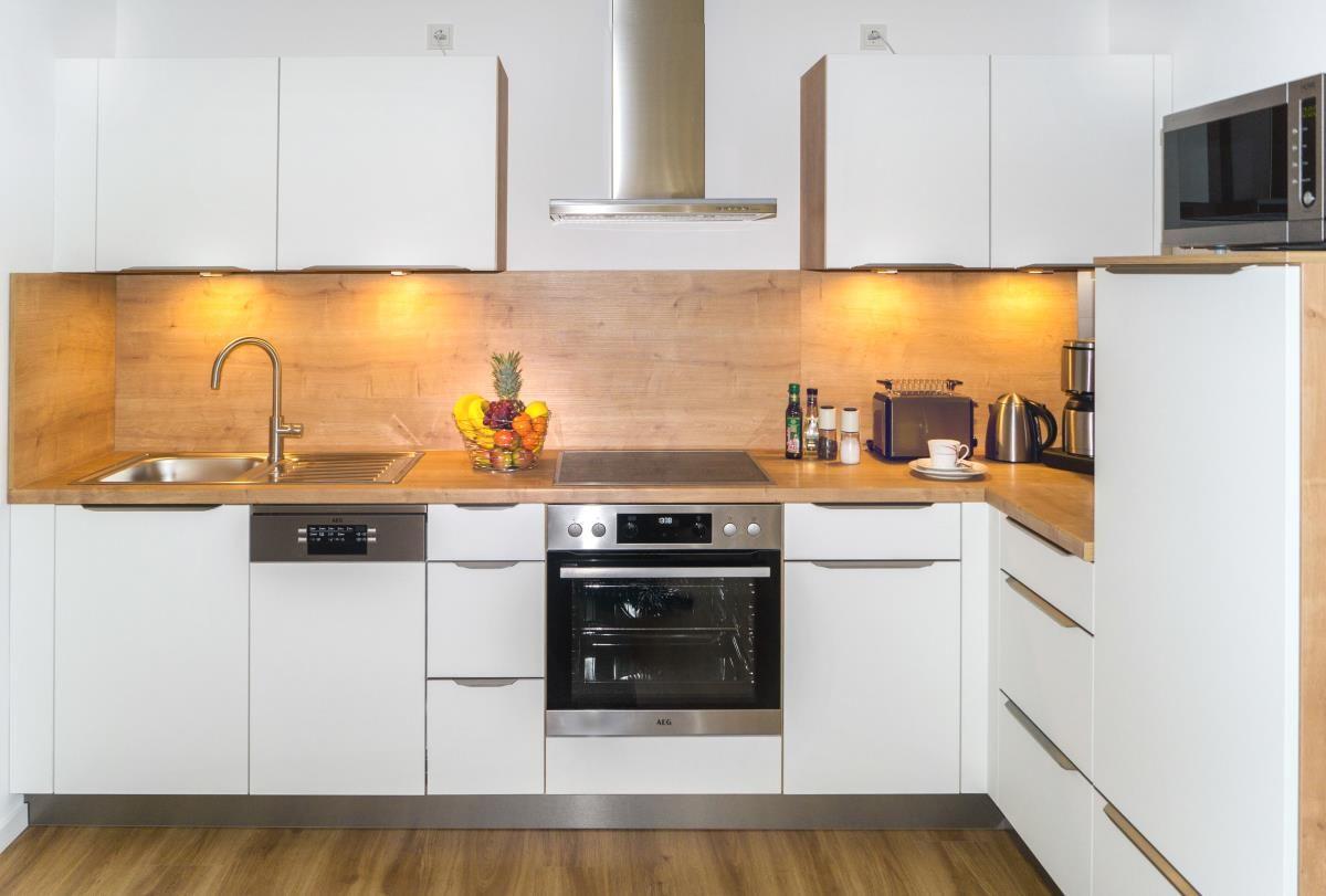 Eingangsbereich mit Holzboden, Spiegel und Schrank. An der Wand hängen Holzregale mit Accessoires.