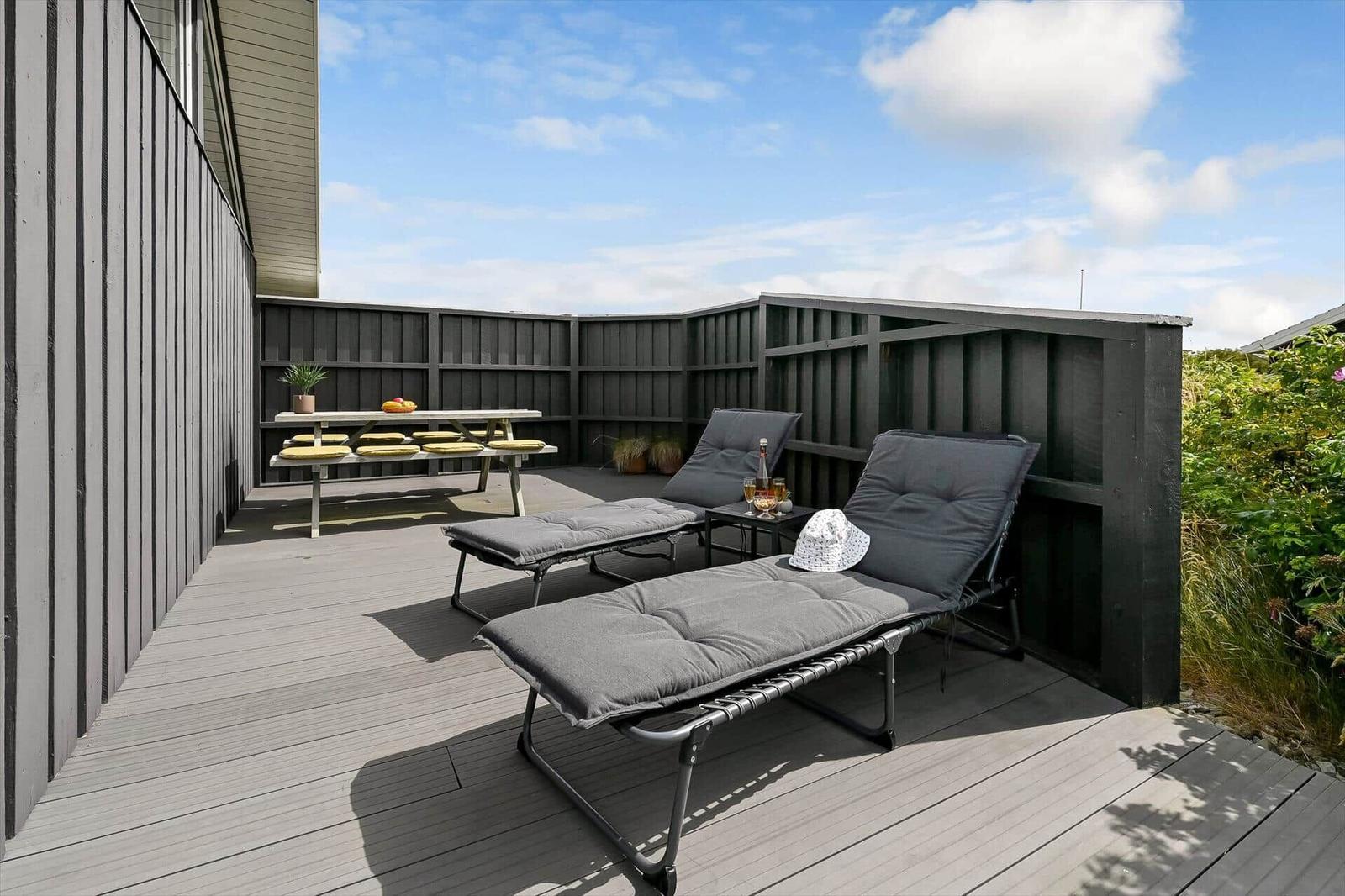 Terrasse mit Tisch, Stühlen und Spielplatte. Tischdecke mit Fransen.