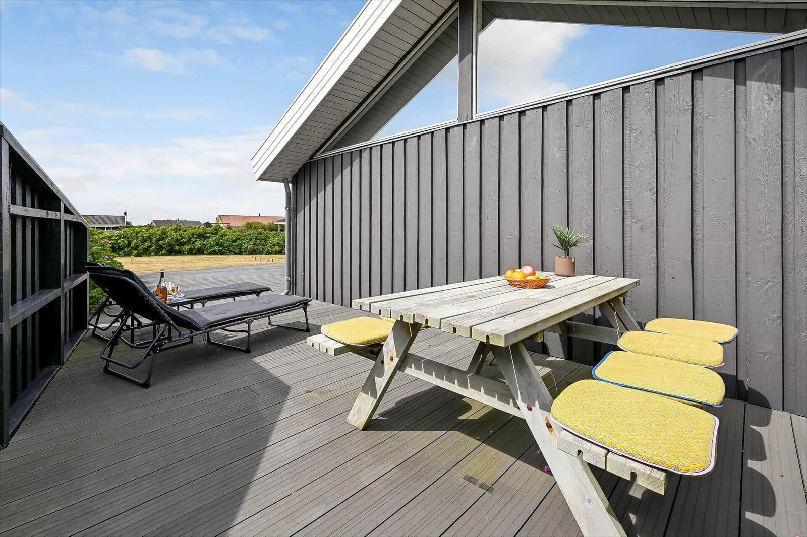 Moderne Villa mit Terrasse, Grill und Garten. Roter Dachziegel und schwarze Fassade.