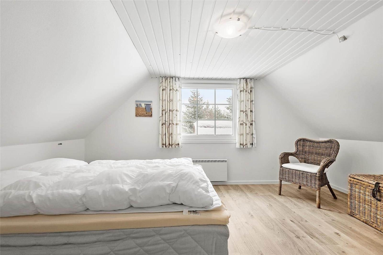 Schlafzimmer mit Dachboden-Decke, Bett, Stuhl und Fenster mit Blick auf Schnee.