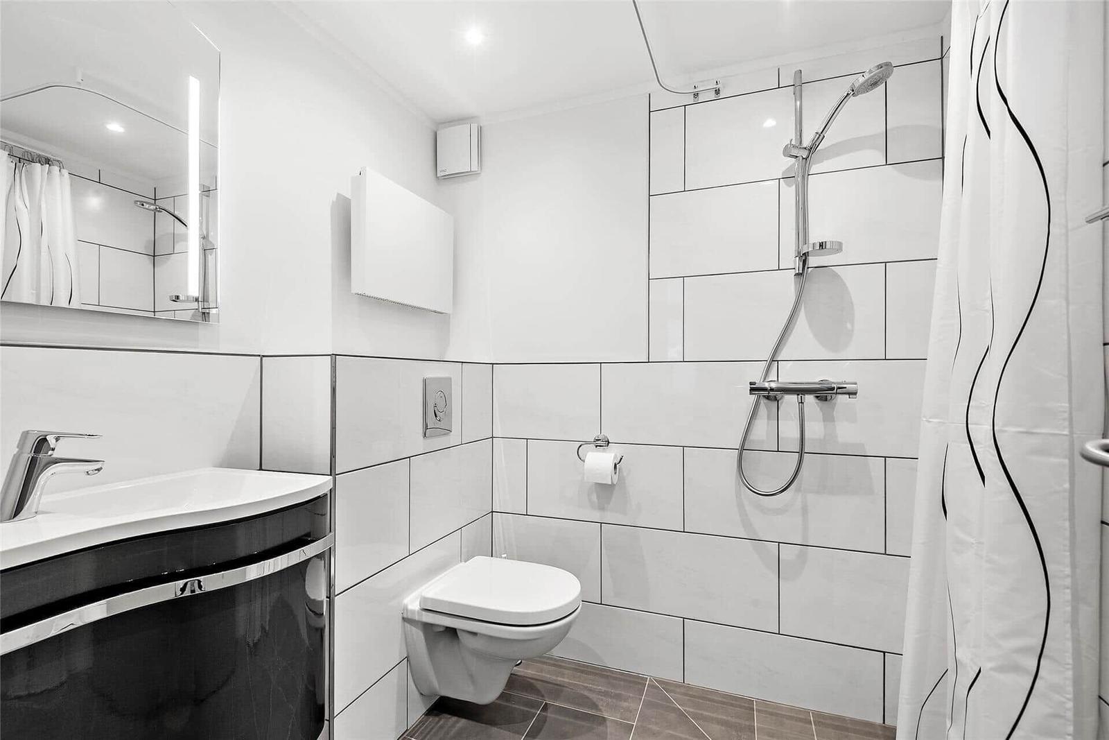 Badezimmer mit Dusche, Toilette und Waschbecken mit Spiegel