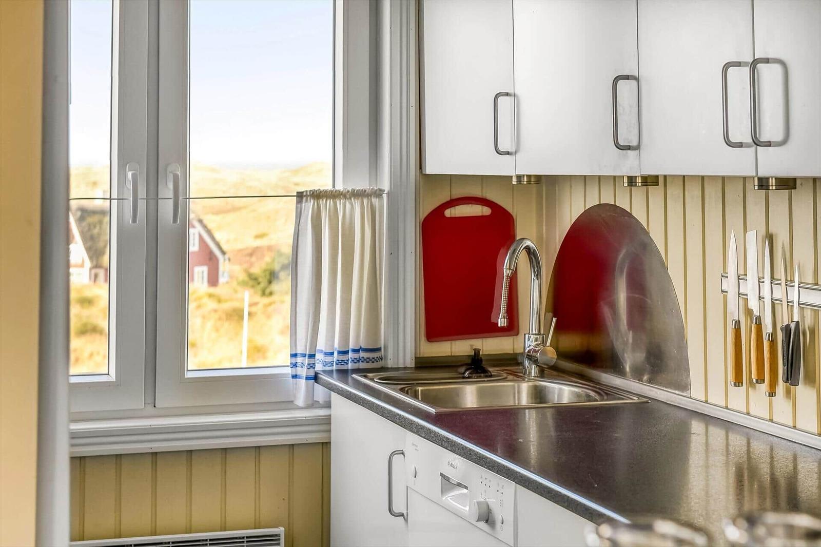 Schreibtisch mit Lampe vor Fenster mit Blick auf Dörfer und Dünen.
