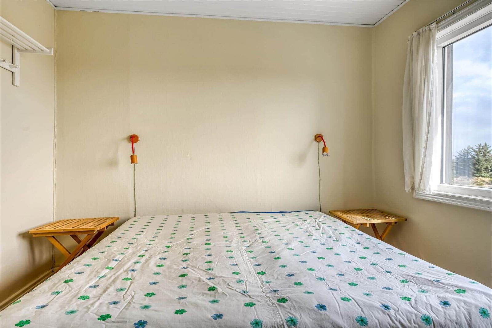 Zimmer mit Holz-Etagenbett, rotem Bettzeug und blau-weißem Teppich.