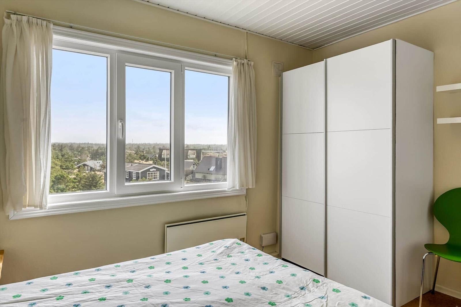 Helle Diele mit Holzwand, Stufen, Sitzgelegenheit und Fenster.