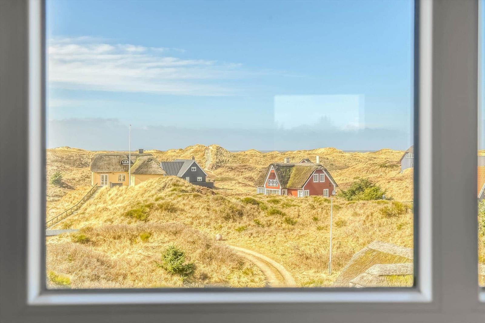 Ein dunkelgraues Haus mit weißem Geländer und Bänken auf der Terrasse.