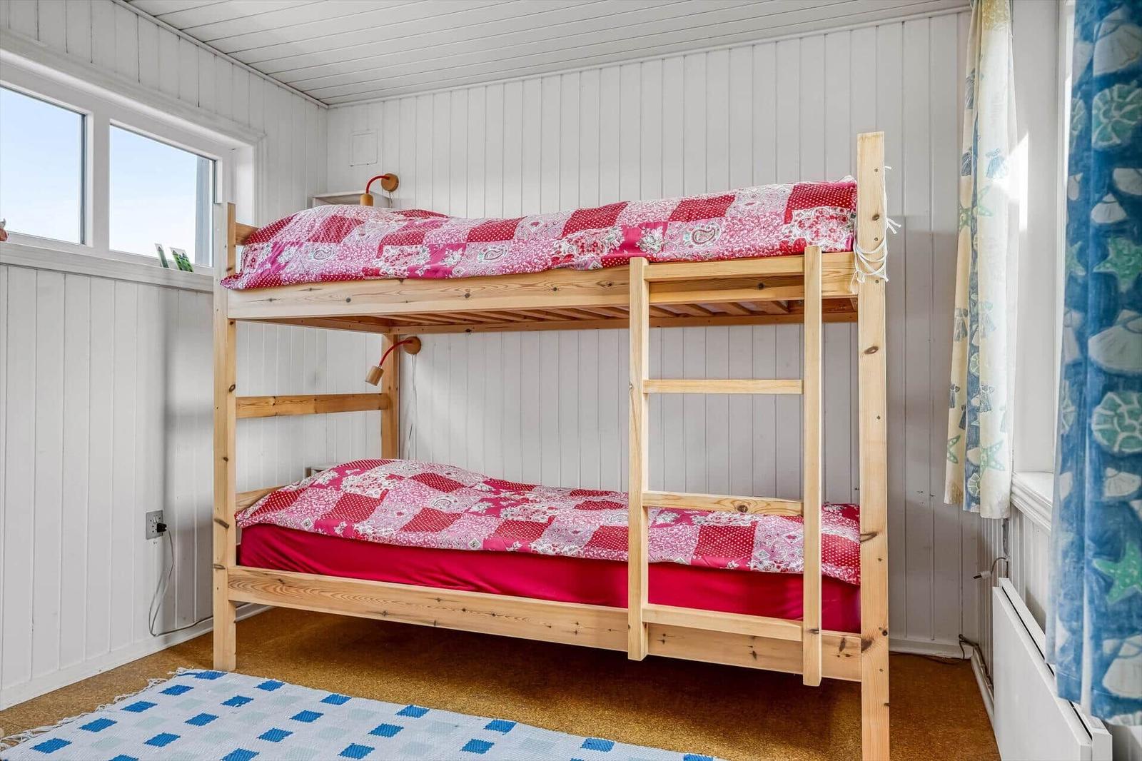 Schwarzes Ferienhaus auf Dünen mit Garage und Weg. Haus mit Fenstern und Schild.