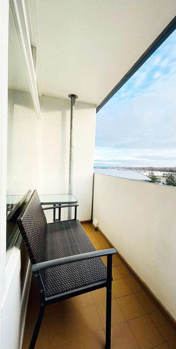 Balkon mit Sitzbank und Tisch, Blick auf Stadt und Himmel