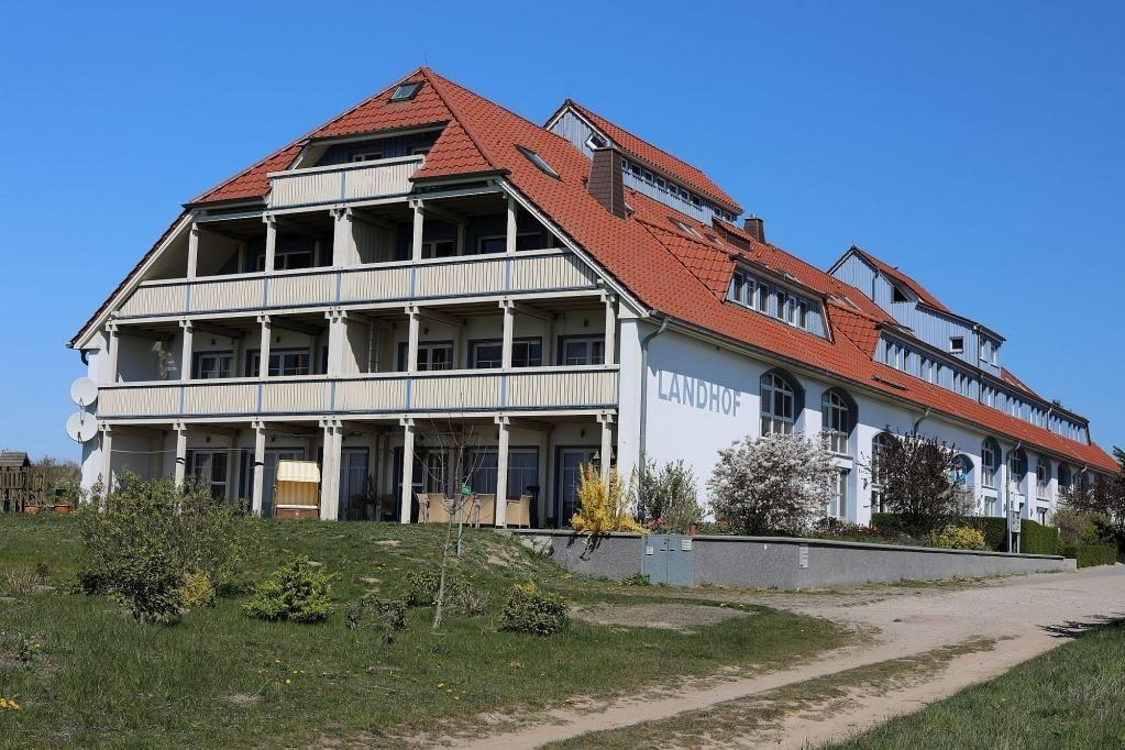 Haus mit rotem Dach am Wasser, Boote vor Anlegestelle