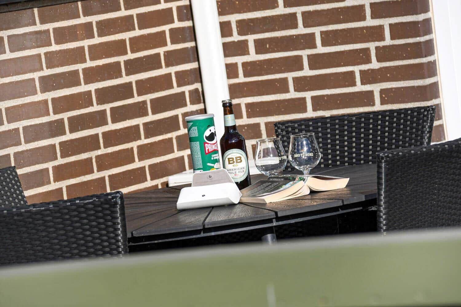 Terrasse mit Tisch und Stühlen, gepflastert, umgeben von Zaun und Grünfläche.