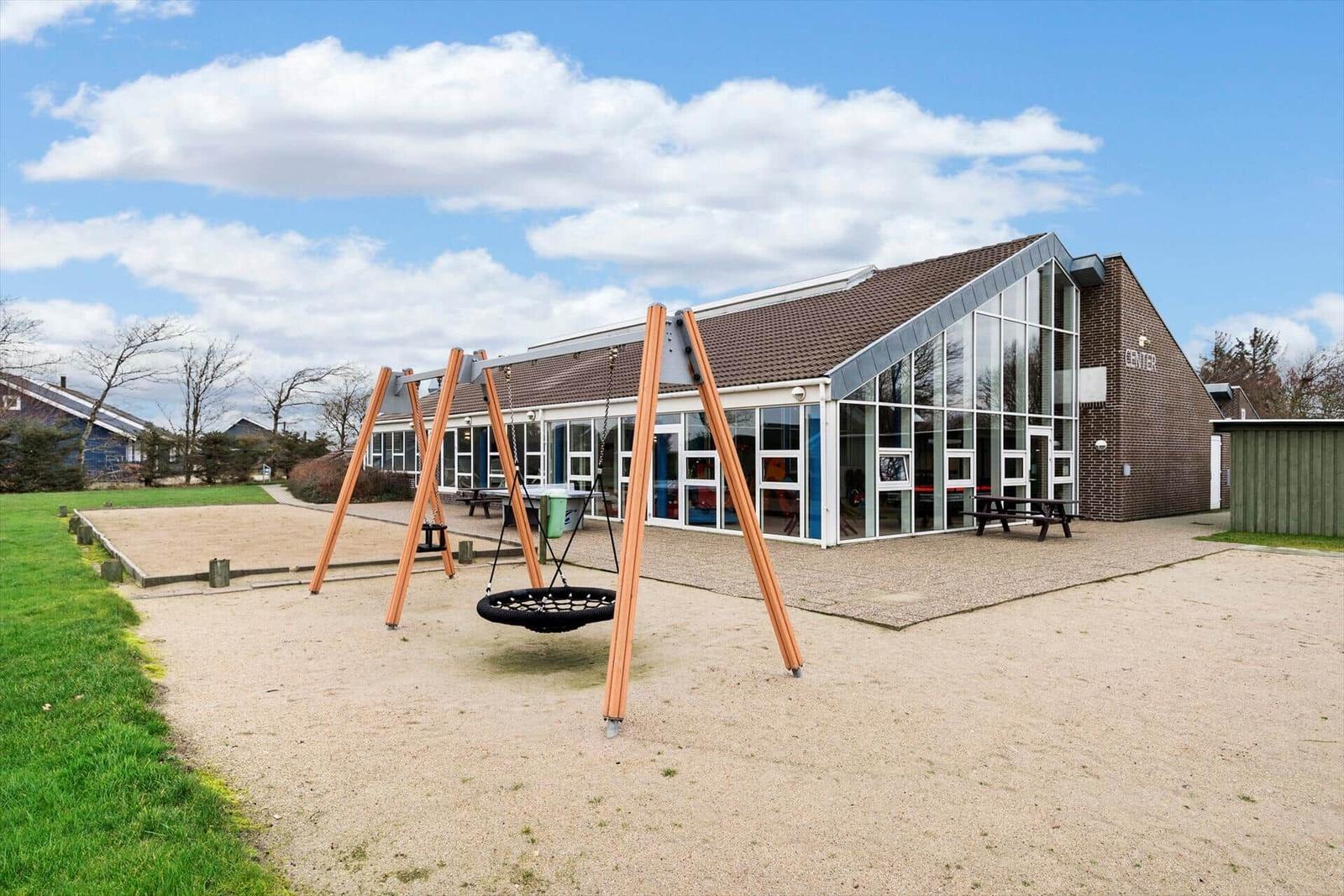 Kinderbereich mit Sandkasten, Spielplatz und Picknicktisch vor Wohnhäusern.