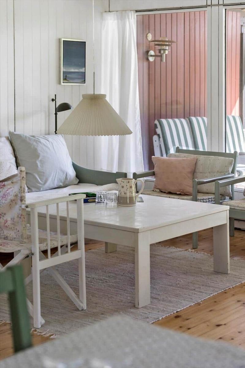 Dining table with four chairs, wall art, and pendant light in white room.