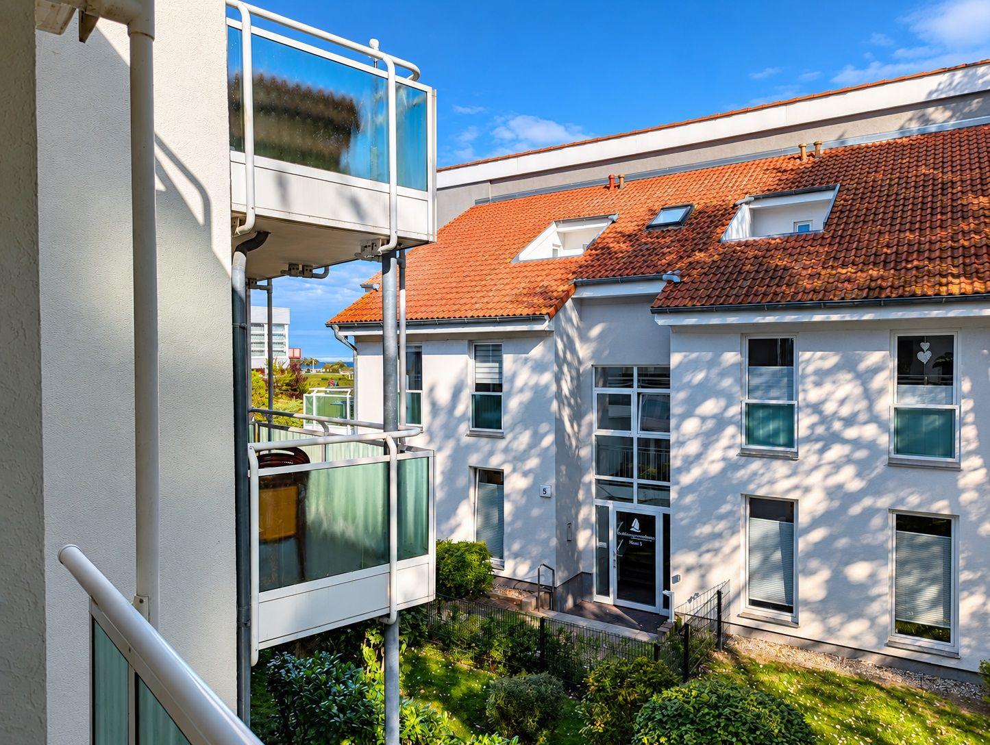 Fassade eines Mehrfamilienhauses mit rotem Dach und Balkonen