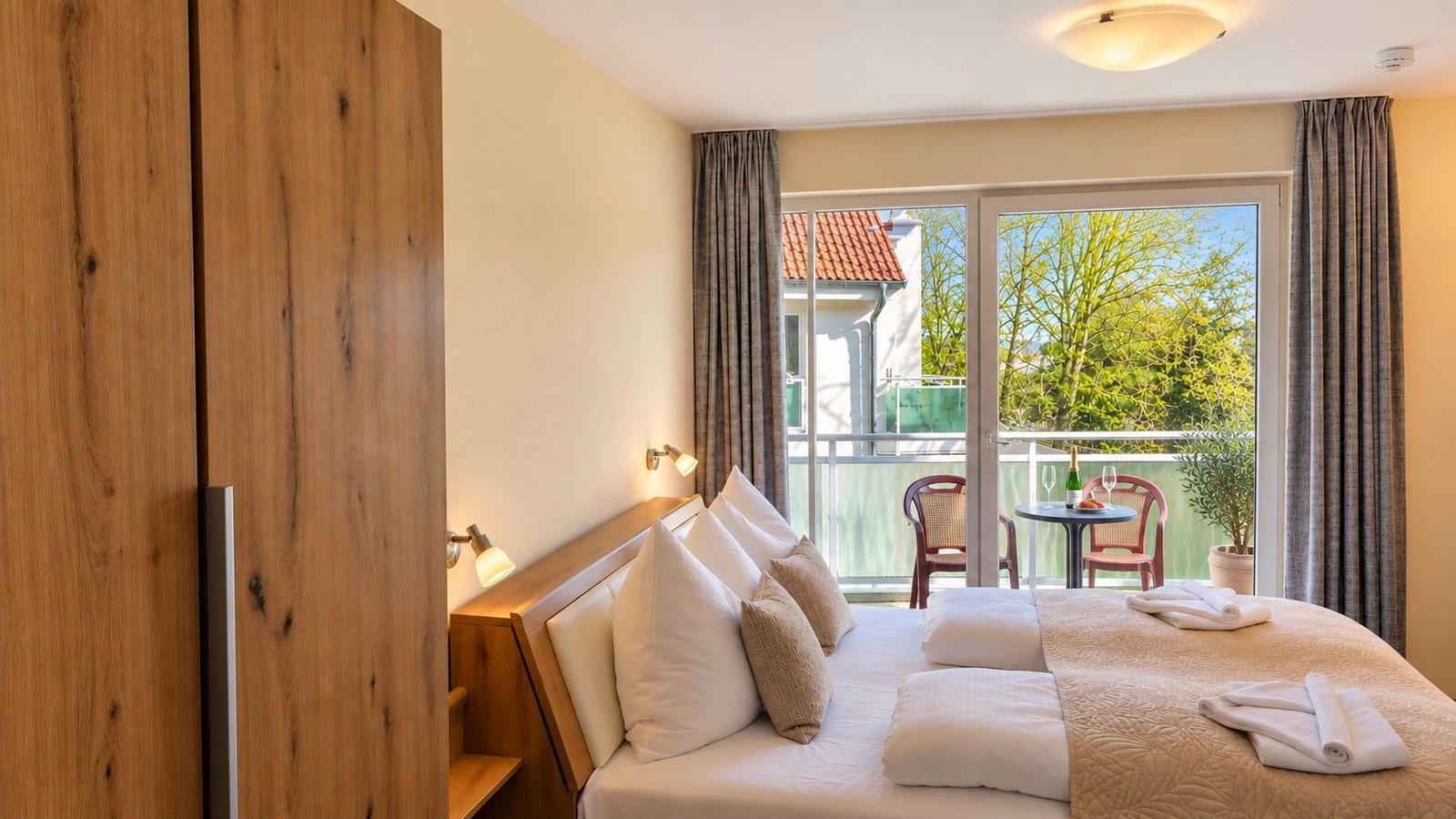 Schlafzimmer mit Bett, Holzschrank und Balkonansicht.