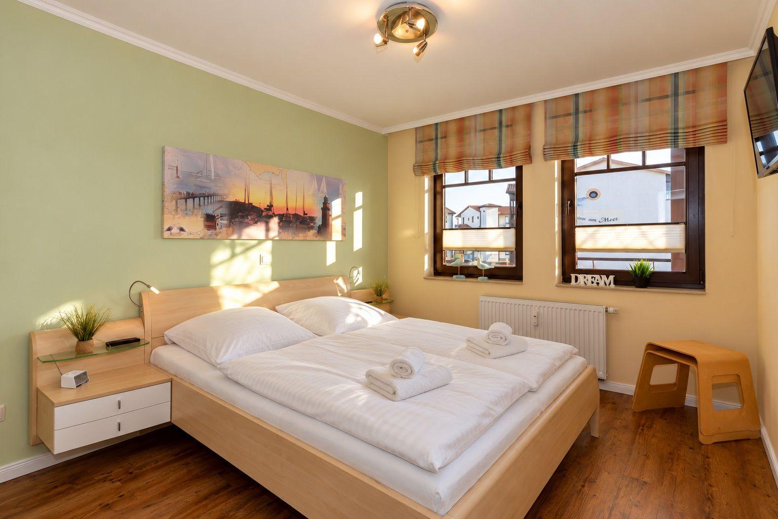 Schlafzimmer mit Doppelbett, Fenster und Nachttisch.