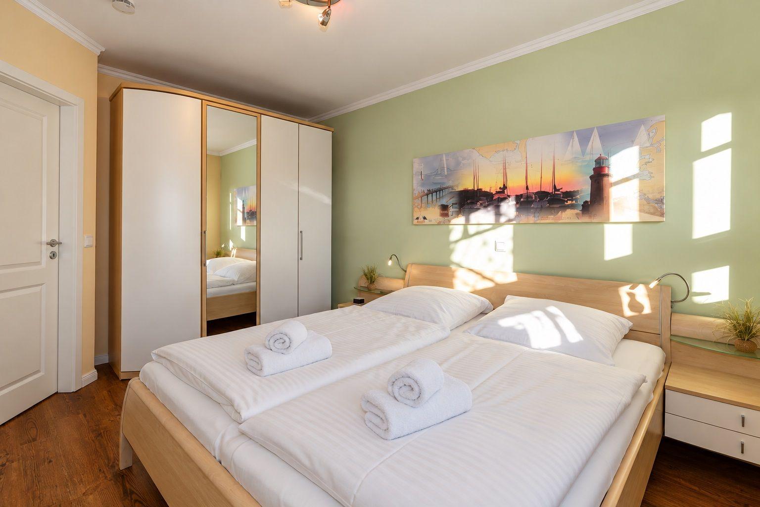 Schlafzimmer mit Doppelbett, Kleiderschrank und Wandbild.