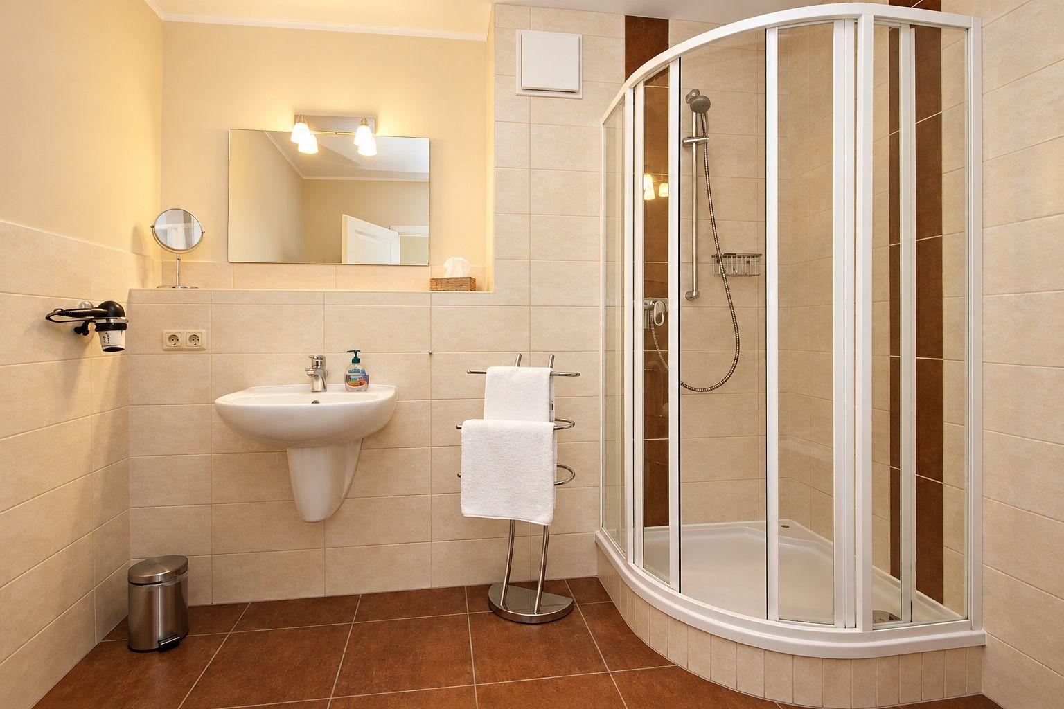 Badezimmer mit Dusche, Waschbecken und Spiegel