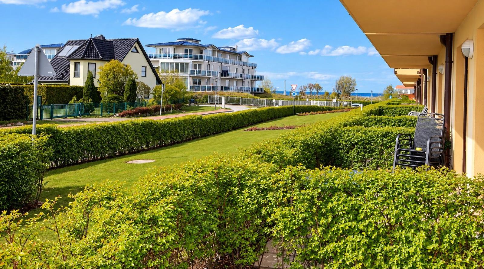 Terrasse mit Stuhl, Blick auf grünen Rasen und Häuser im Hintergrund.