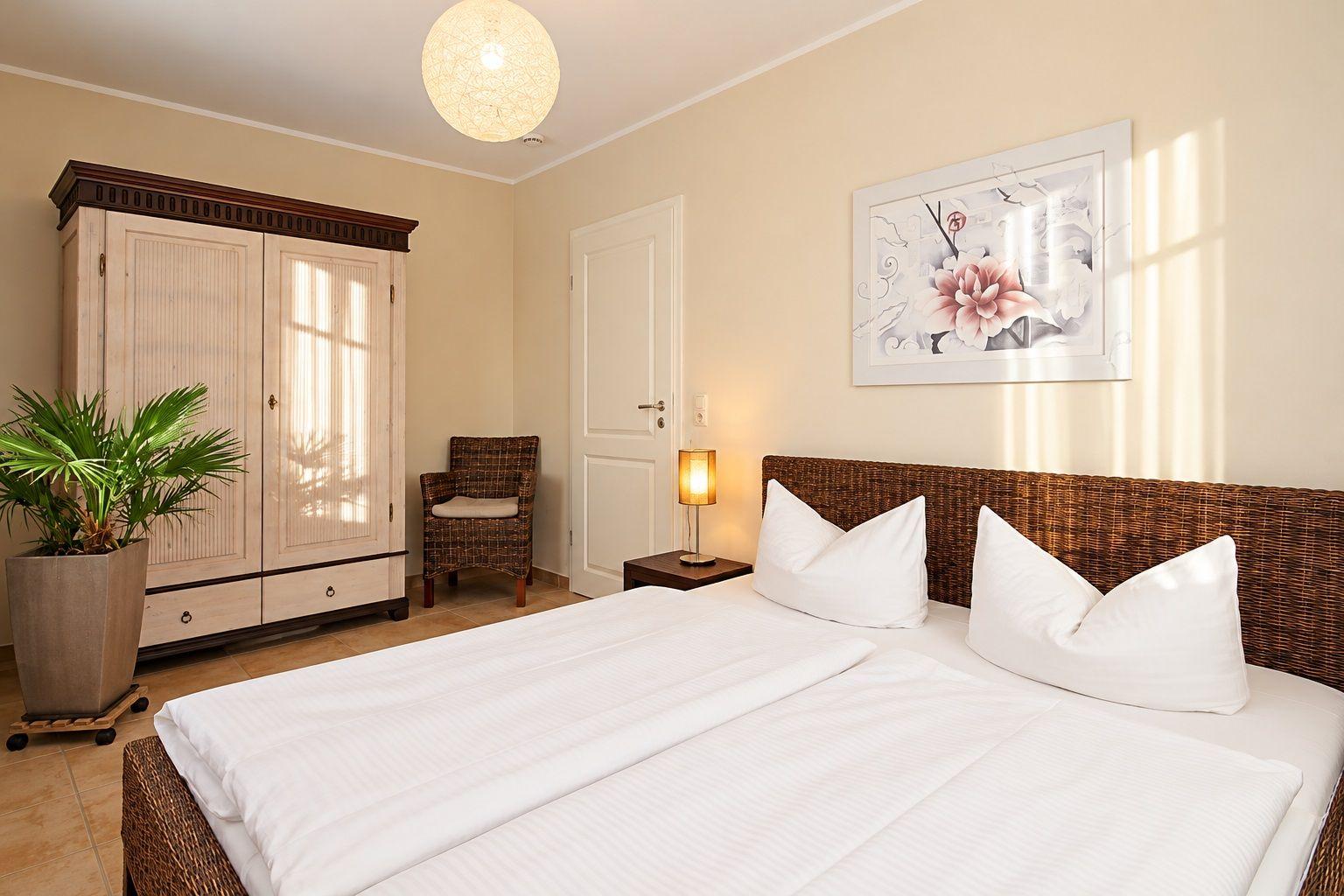 Schlafzimmer mit Doppelbett, Kleiderschrank und Sitzgelegenheit.