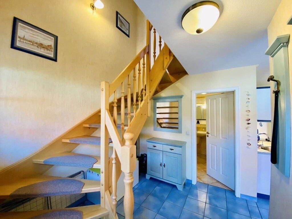 Schlafzimmer mit Dachschrägen, Holzboden und grünem Schrank. Fenster mit blauen Vorhängen.